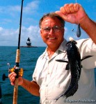 Captain Bob Rocchetta holds up a black sea bass with a lighthouse in the background